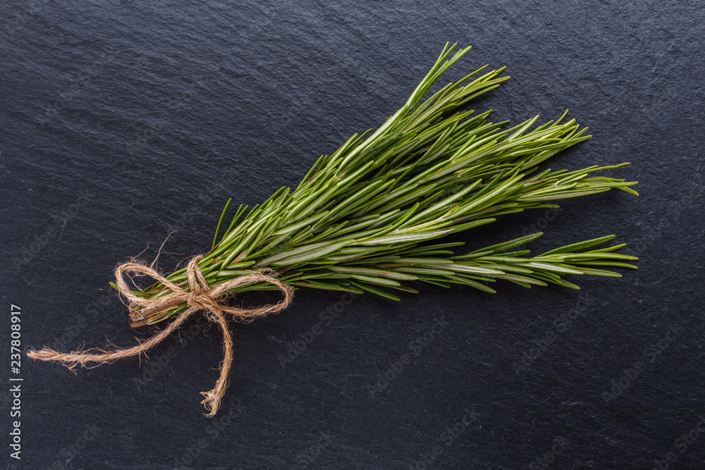 Rosemary essential oil on dark stone background Rosemary essential oil on dark stone background