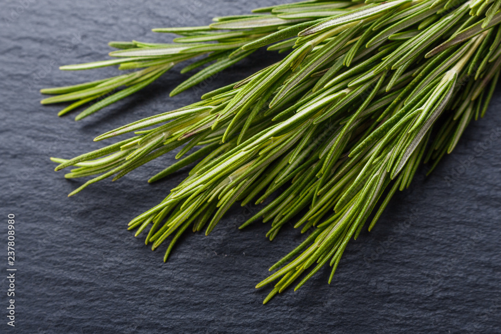 Rosemary essential oil on dark stone background Rosemary essential oil on dark stone background