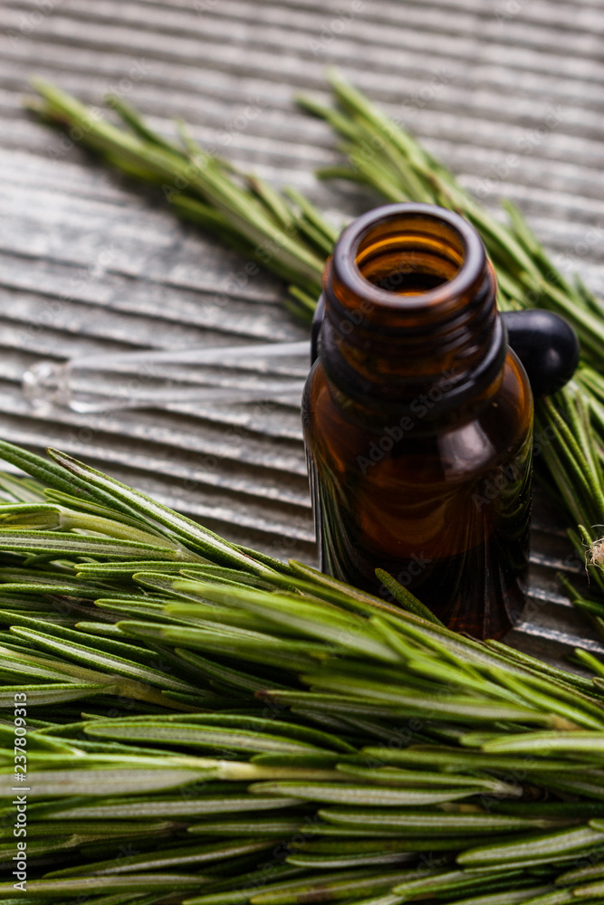 Rosemary essential oil on a gray wooden rustic background Rosemary essential oil on a gray wooden rustic background