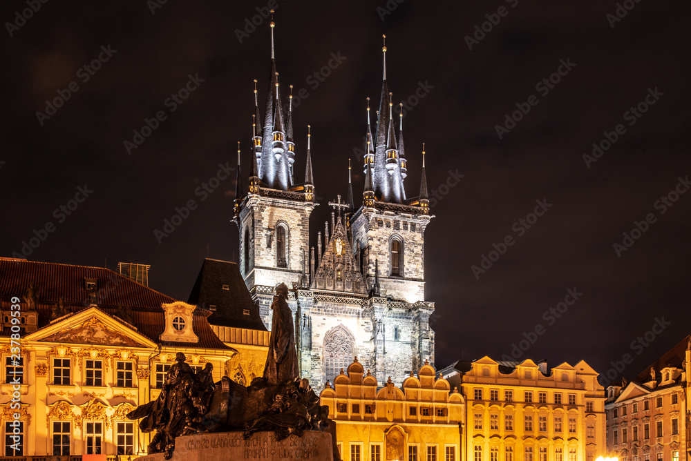 Two gothic towers of Church Of Our Lady Before Tyn and Jan Hus Memorial at Old Town Square by night. Prague, Czech Republic.