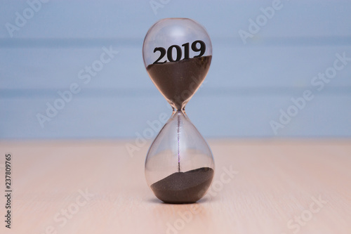 New Year 2019 concept. Time running out concept with hourglass falling sand from 2018.