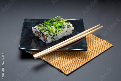 Black plate with american rolls and chopsticks