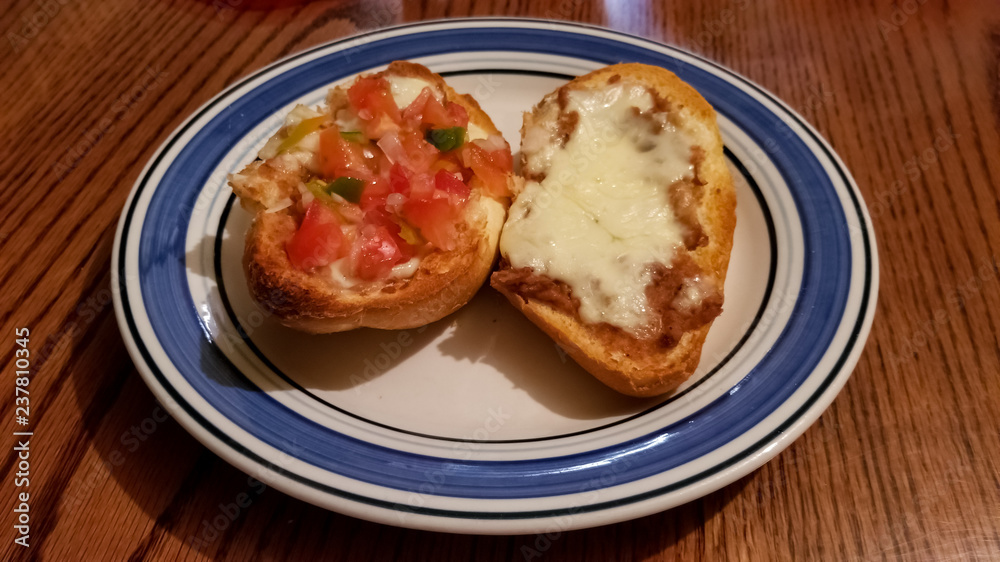 Mollete, delicious typical Mexican food. Sliced bread roll bolillo with refried beans, melted cheese and pico de gallo.