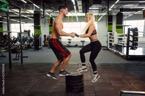 Muscular healthy guy and his sporty girlfriend training together in the gym.
