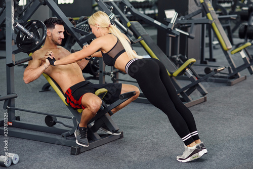 Muscular healthy guy and his sporty girlfriend training together in the gym. Lovely couple training together at the gym. Fitness and bodybuilding concept.