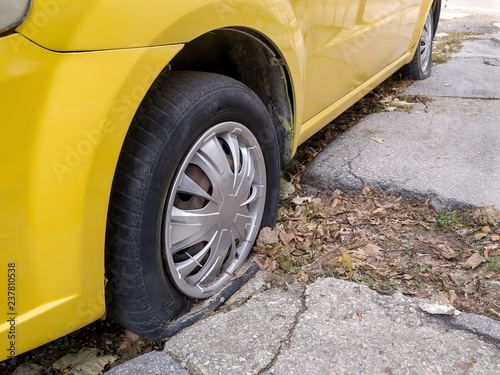 Close up of flat or pierced tires of a yellow car or taxi on a city street