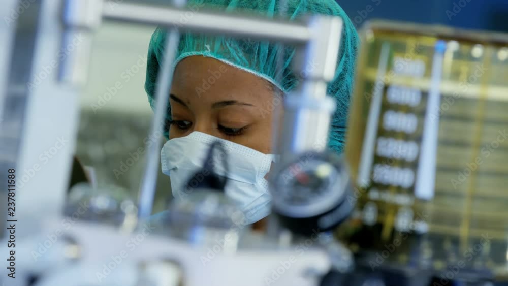 Professional Multi ethnic female Anesthesiologist monitoring anesthesia machine equipment during patient operation in hospital theater 