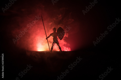 Medieval battle scene. Silhouettes of figures as separate objects, fight between warriors on dark toned foggy background. Night scene.