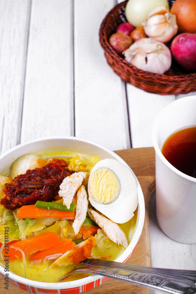 Lontong-Traditional Malaysian and   Indonesian food on wooden table with spoon.