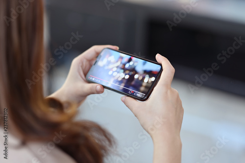 Cropped shot of female hand holding mobile phone playing video stream online photo