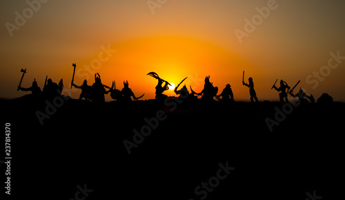 Medieval battle scene with cavalry and infantry. Silhouettes of figures as separate objects  fight between warriors on sunset foggy background.