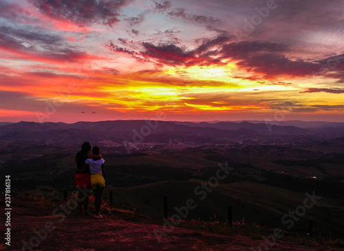 Girl couple embracing each other, contemplating a beautiful sunset in Pedra Bela Vista, (Socorro/SP, Brazil)