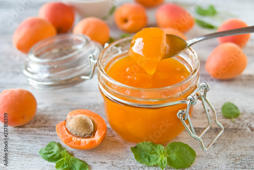 jar with homemade apricot jam on a light wooden background