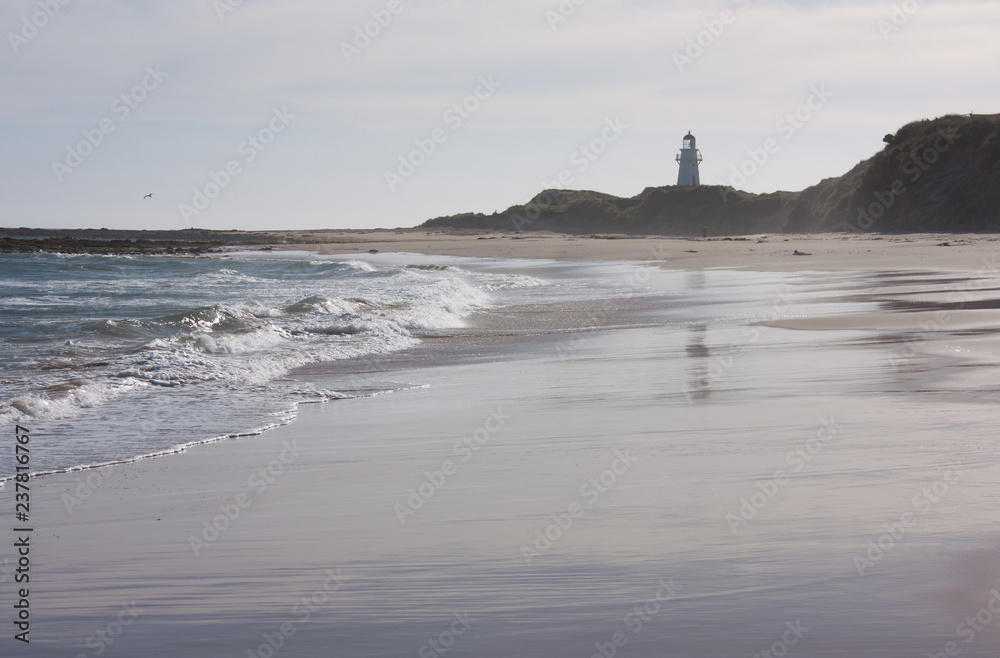 A beach and a lighthouse in the distance at Waipapa Point in the Catlins in the South Island in New Zealand