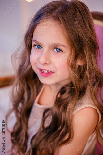 Portrait of a little girl with curly hair on Christmas Eve, the New Year will bring gifts.