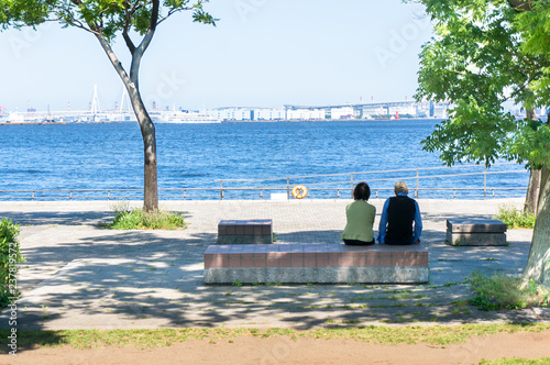 海辺の公園でベンチに座る老夫婦の後ろ姿
