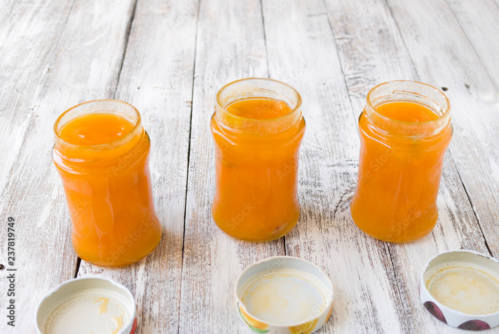 jar with homemade apricot jam on a light wooden background jar with homemade apricot jam on a light wooden background