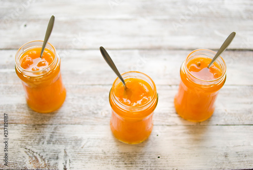 jar with homemade apricot jam on a light wooden background