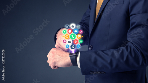 Businessman wearing smartwatch with colored application symbols on it.