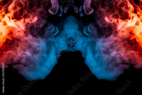 A dynamic explosion of puffs of smoke of light blue pink and red colors on a black background with smooth flames rendering an isolated pattern. Decorative wallpaper with multi-colored swirl of smoke.