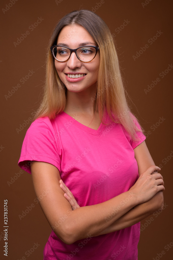 Studio shot of young beautiful woman smiling against brown background Studio shot of young beautiful woman smiling against brown background
