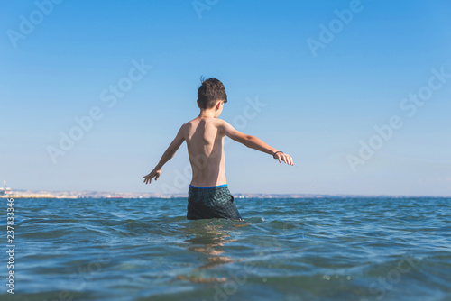 Teen  boy in the wave of the sea on the beach 