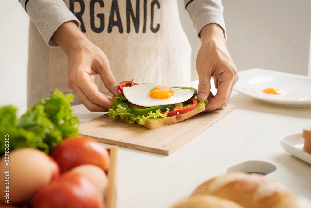 Hands of man prepare breakfast with sandwich with poached eggs