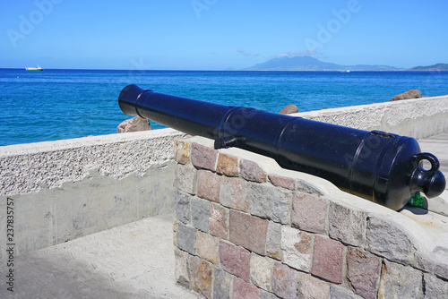 View of a colonial cannon pointed towards the Caribbean Sea in Charlestown, the capital of Nevis in the Federation of St Kitts and Nevis in the West Indies