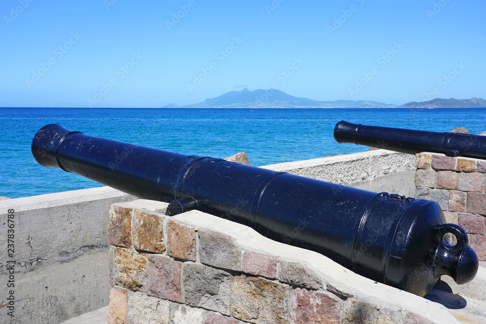 View of a colonial cannon pointed towards the Caribbean Sea in Charlestown, the capital of Nevis in the Federation of St Kitts and Nevis in the West Indies View of a colonial cannon pointed towards the Caribbean Sea in Charlestown, the capital of Nevis in the Federation of St Kitts and Nevis in the West Indies