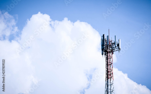 Tower poles and wireless telephone antennas against blue sky background.