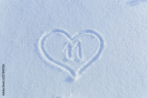 The number eleven drawn on the snow surrounded by a frame in the form of a heart.