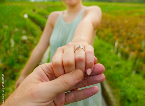 close up couple hands man holding happy fiance hand with diamond engagement ring on her finger after wedding proposal at tropical beautiful and romantic spot