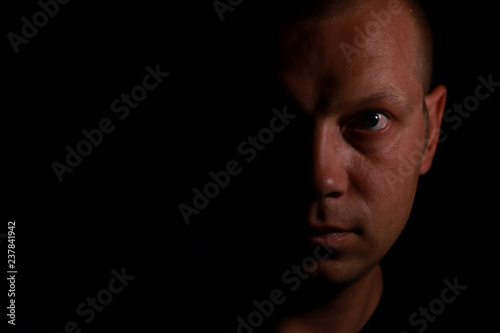Portrait of a serious man face in darkness.