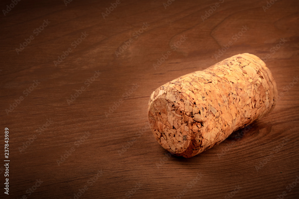 A closeup photo of a champagne cork on a dark rustic wooden background with copyspace