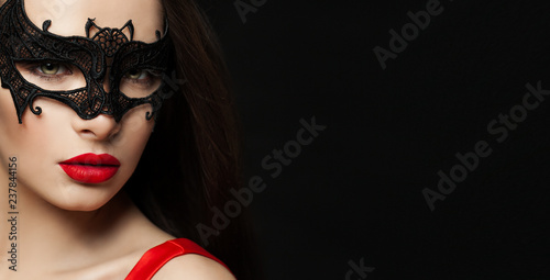 Beautiful womanwith red lips makeup wearing carnival mask on black background with copy space