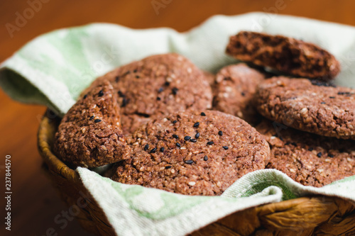 Homemade chocolate oatmeal cookies with white and black sesame seeds on a brown wooden table