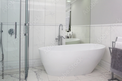The bathroom has a modern style and marble tiles.