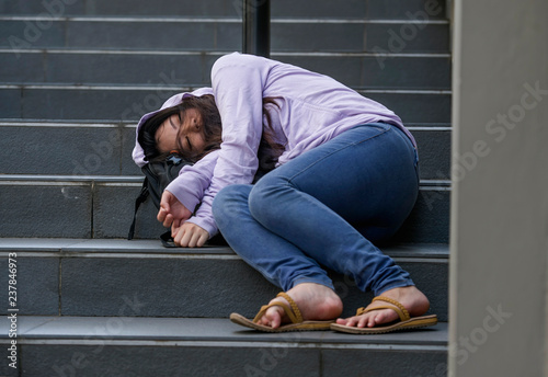 oung depressed and intoxicated Asian student woman or teenager girl sitting on street staircase drunk or high on drugs suffering addiction problem and anxiety