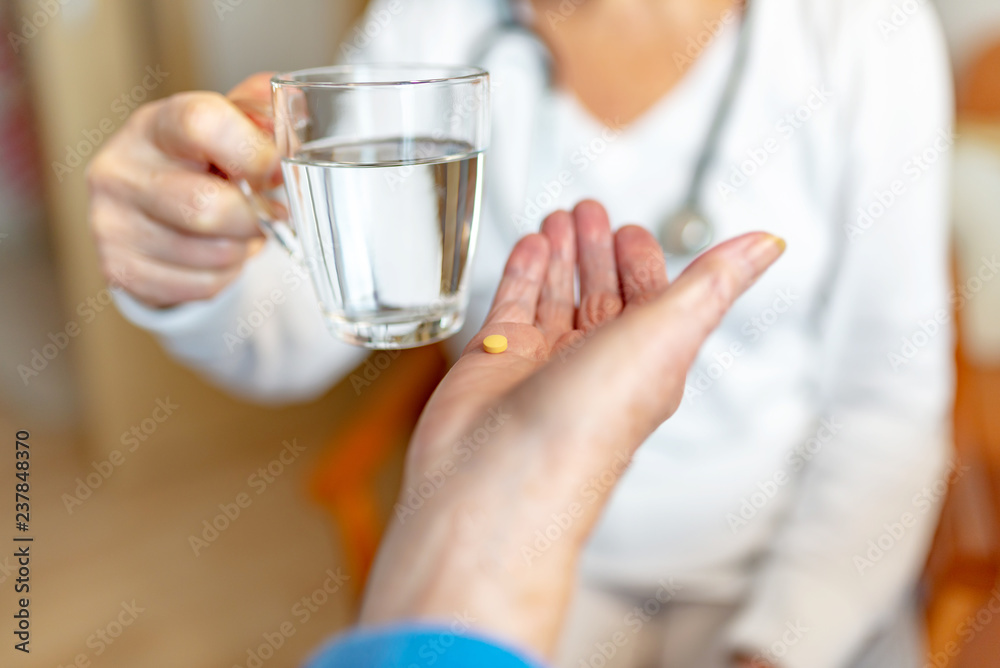 Pflegekraft reicht Rentnerin ein Glas Wasser für die Medikamente Pflegekraft reicht Rentnerin ein Glas Wasser für die Medikamente