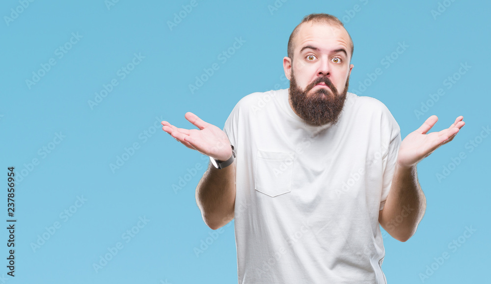 Fototapeta premium Young caucasian hipster man wearing casual t-shirt over isolated background clueless and confused expression with arms and hands raised. Doubt concept.