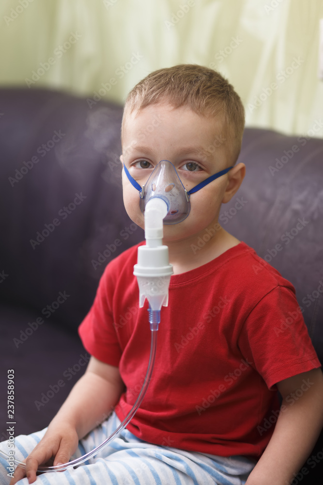 Caucasian boy inhales couples containing medication to stop coughing.