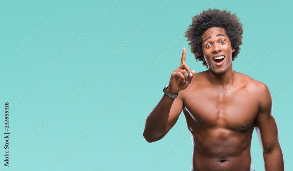 Afro american shirtless man showing nude body over isolated background pointing finger up with successful idea. Exited and happy. Number one.