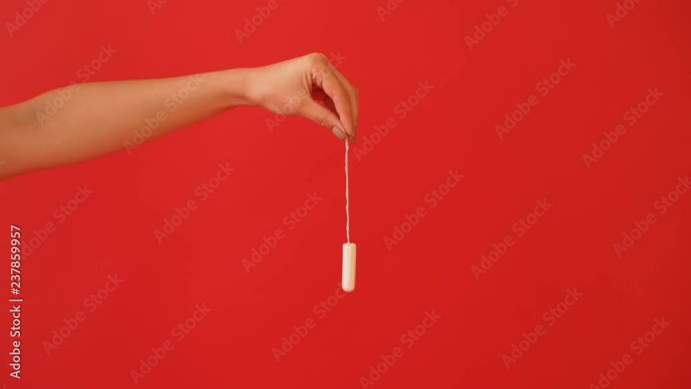 The concept of menstruation, ovulation in girls. Girl on a red background holding a tampon, gasket. The concept of menstruation, ovulation in girls. Girl on a red background holding a tampon, gasket.