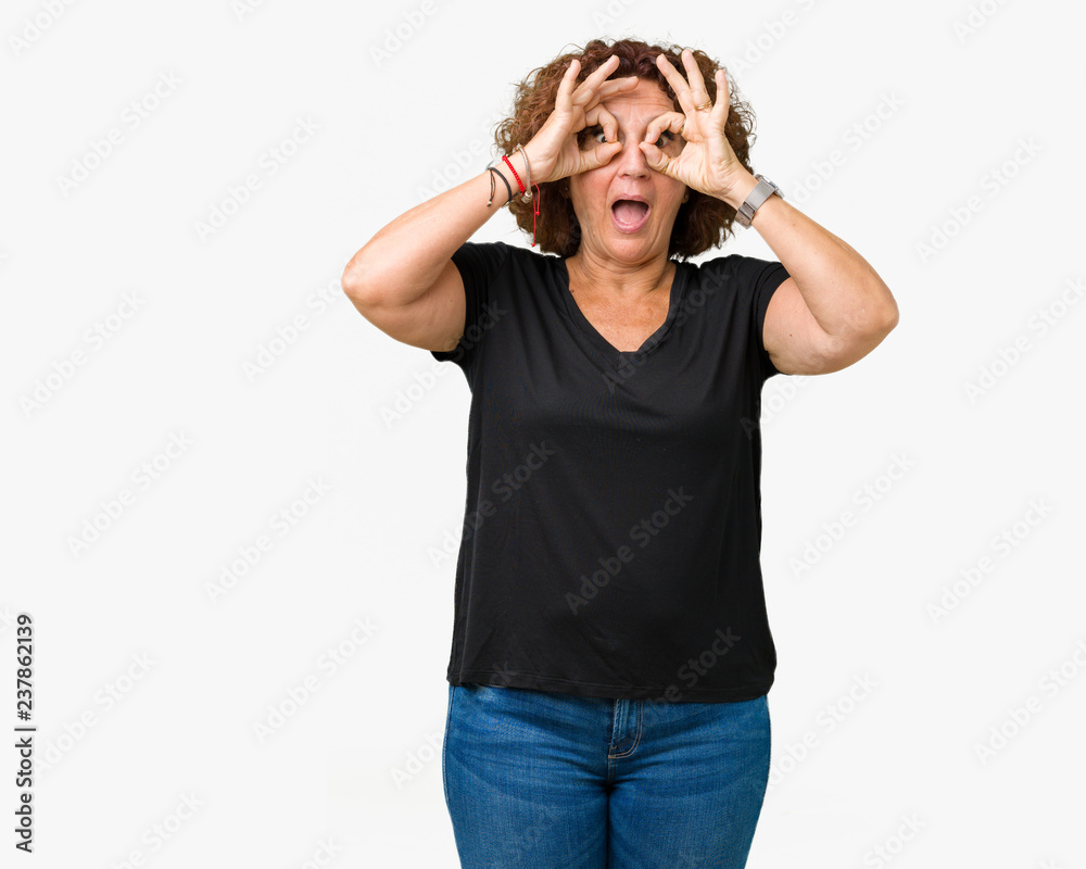 Beautiful middle ager senior woman over isolated background doing ok gesture like binoculars sticking tongue out, eyes looking through fingers. Crazy expression.