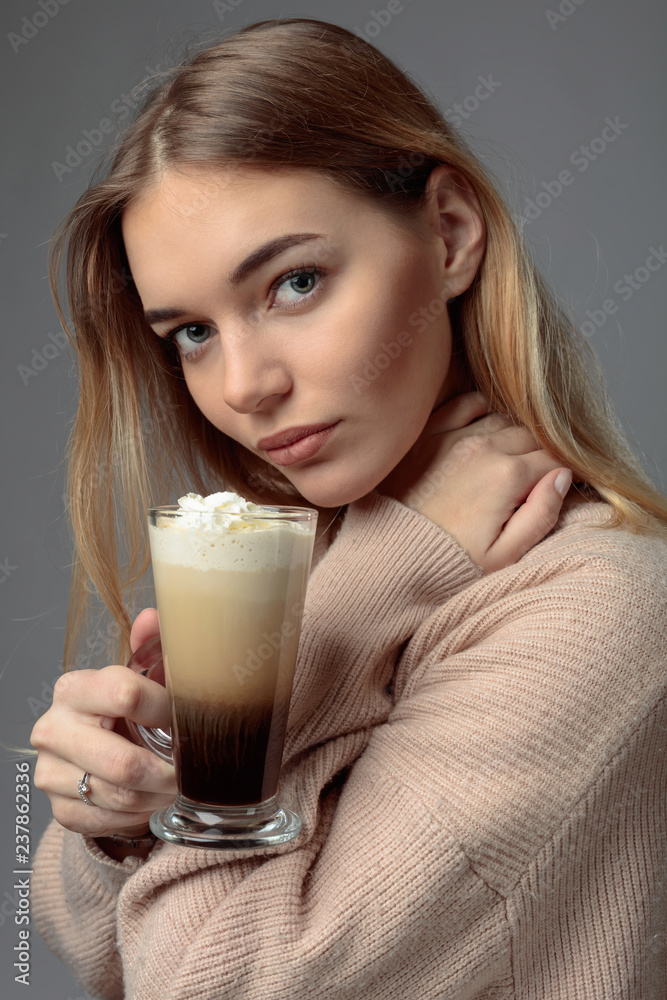 Beautiful blonde in a sweater holding a mug of coffee with cream. Beautiful blonde in a sweater holding a mug of coffee with cream.
