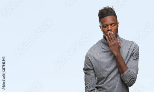 Young african american man over isolated background bored yawning tired covering mouth with hand. Restless and sleepiness.