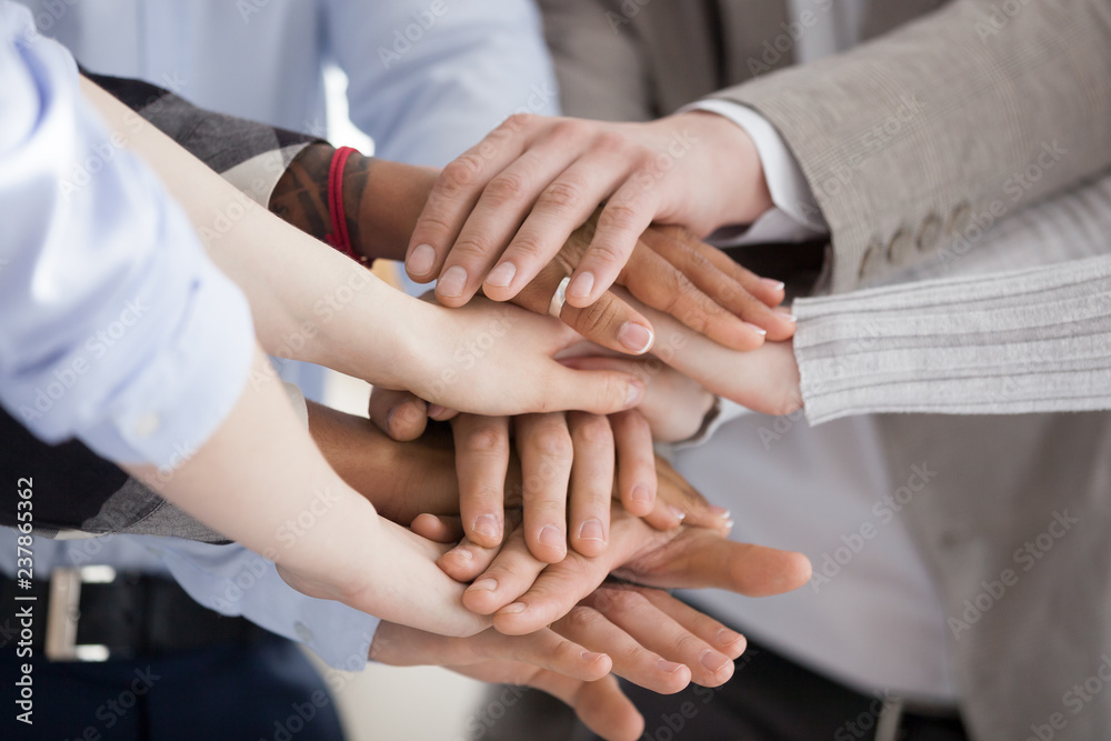 Close up of diverse workers or employees put hands in stack showing support and unity, reach shared goal together, multiracial people engaged in teambuilding activity or training. Teamwork concept Close up of diverse workers or employees put hands in stack showing support and unity, reach shared goal together, multiracial people engaged in teambuilding activity or training. Teamwork concept