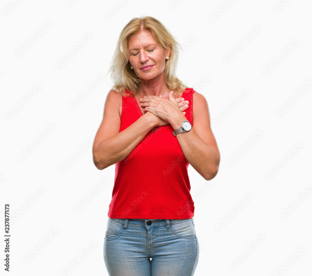 Middle age blonde woman over isolated background smiling with hands on chest with closed eyes and grateful gesture on face. Health concept. Middle age blonde woman over isolated background smiling with hands on chest with closed eyes and grateful gesture on face. Health concept.