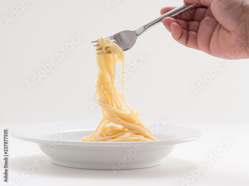 hand holding roll pasta spaghetti with a fork and bish photo