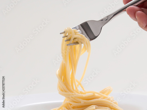 hand holding roll pasta spaghetti with a fork and bish photo